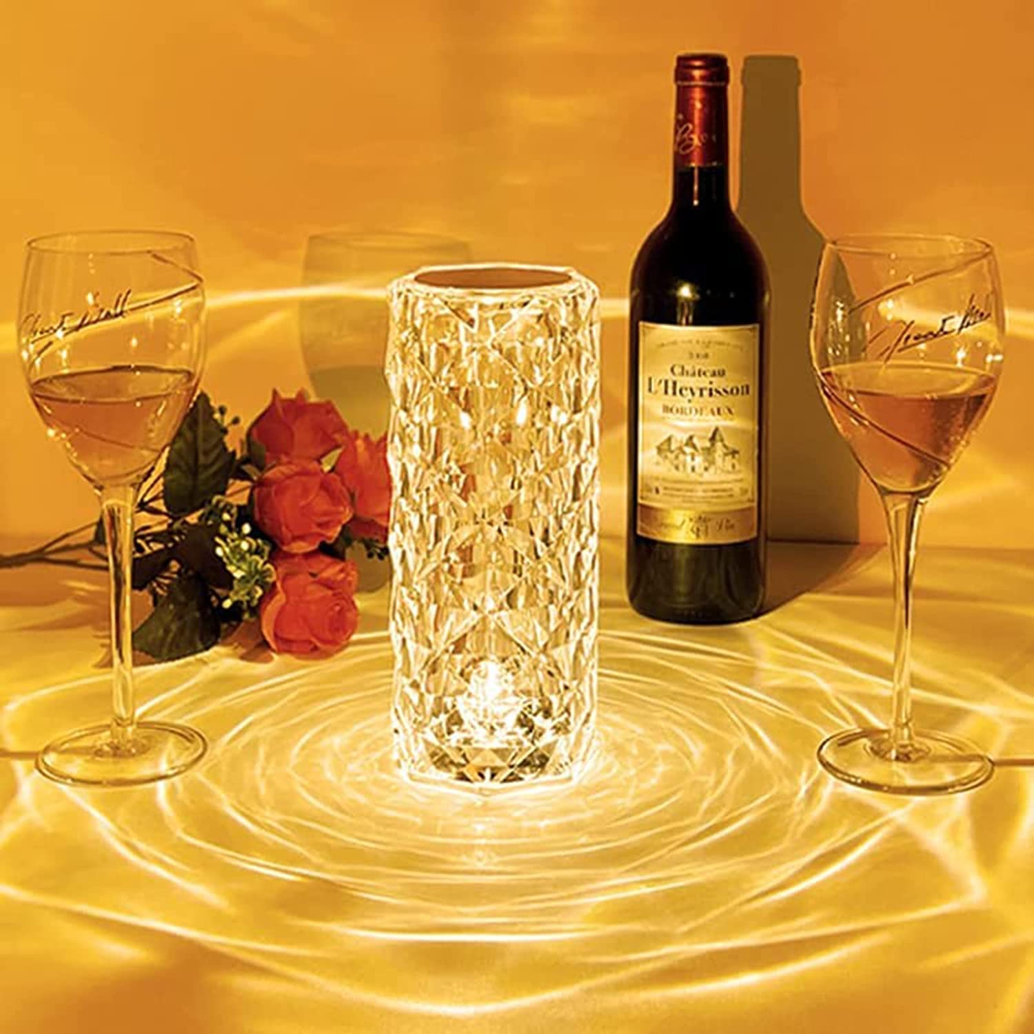 Wine glasses, bottle, and decorative candle on a table with a warm glow.
